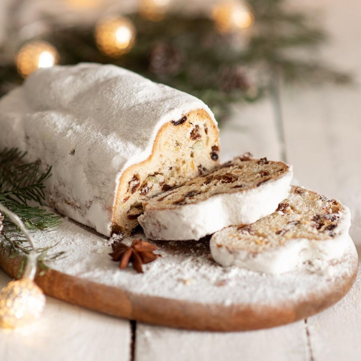 A Dresdner Stollen dusted with icing sugar, sliced on a board.